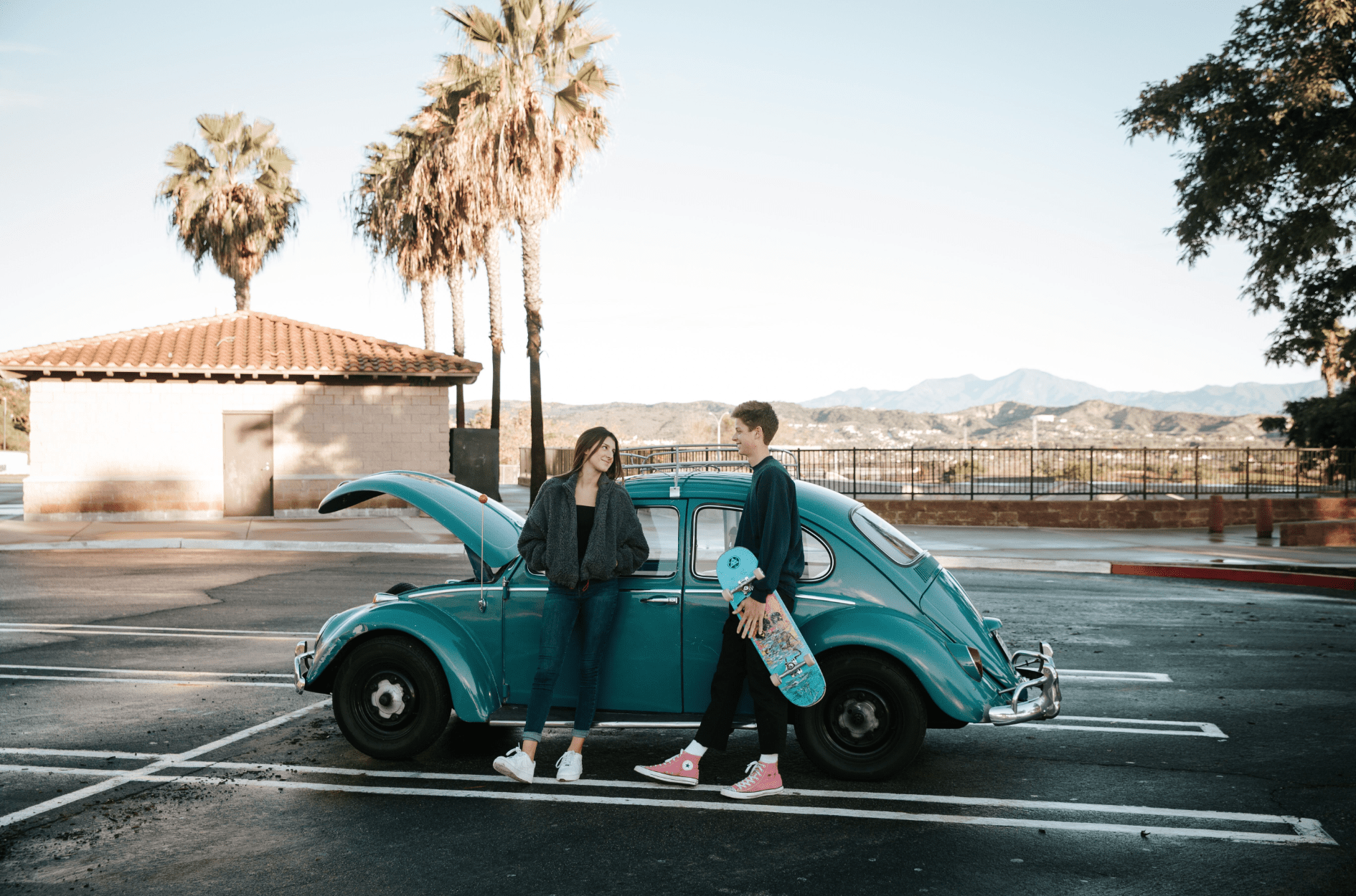 Skateboarder guy and a girl in front of a VW bug