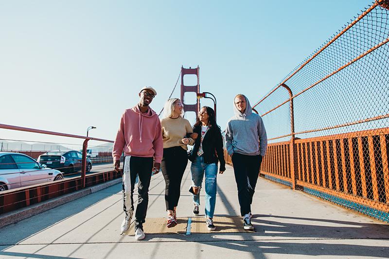 Four people walking over bridge