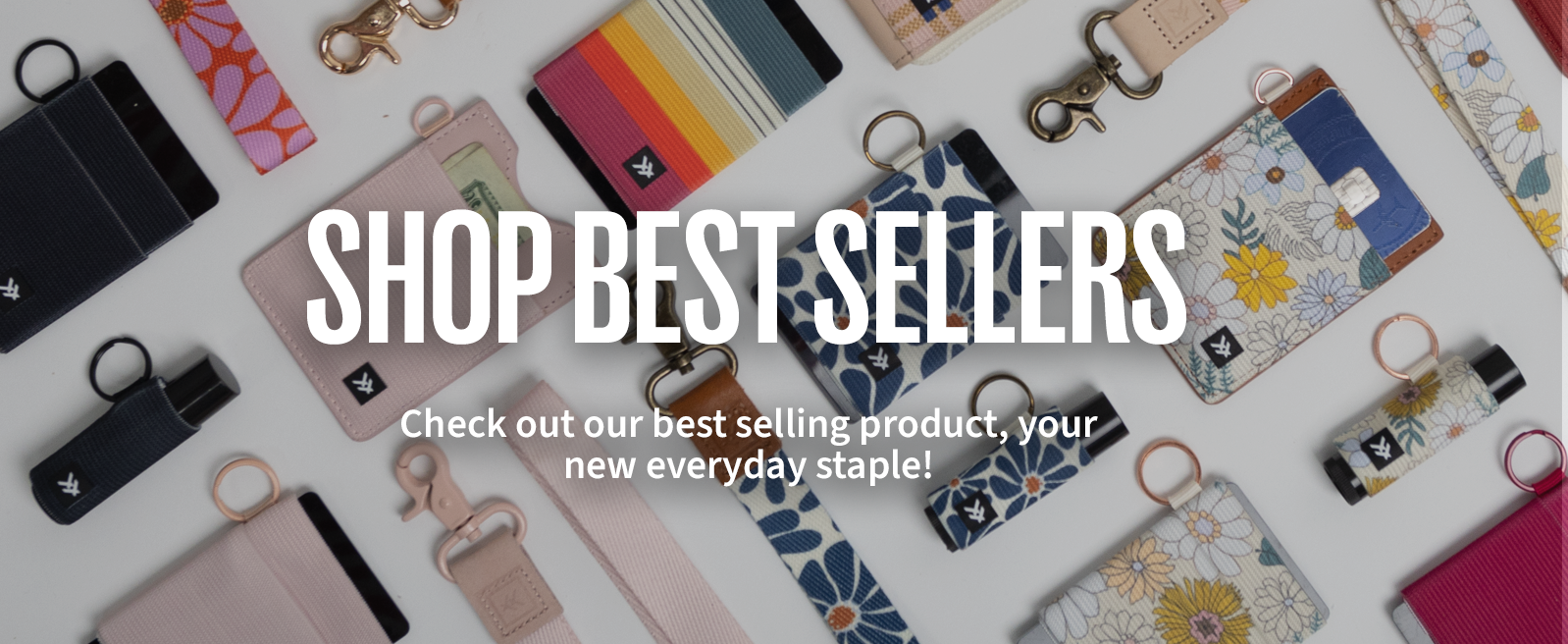 an assortment of wallets and keychains on a white table serve as a backdrop for white text which says "Shop Best Sellers.  Check out our best selling product, your new everday staple!"