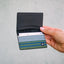 Black leather bifold wallet with navy, olive, and white striped elastic