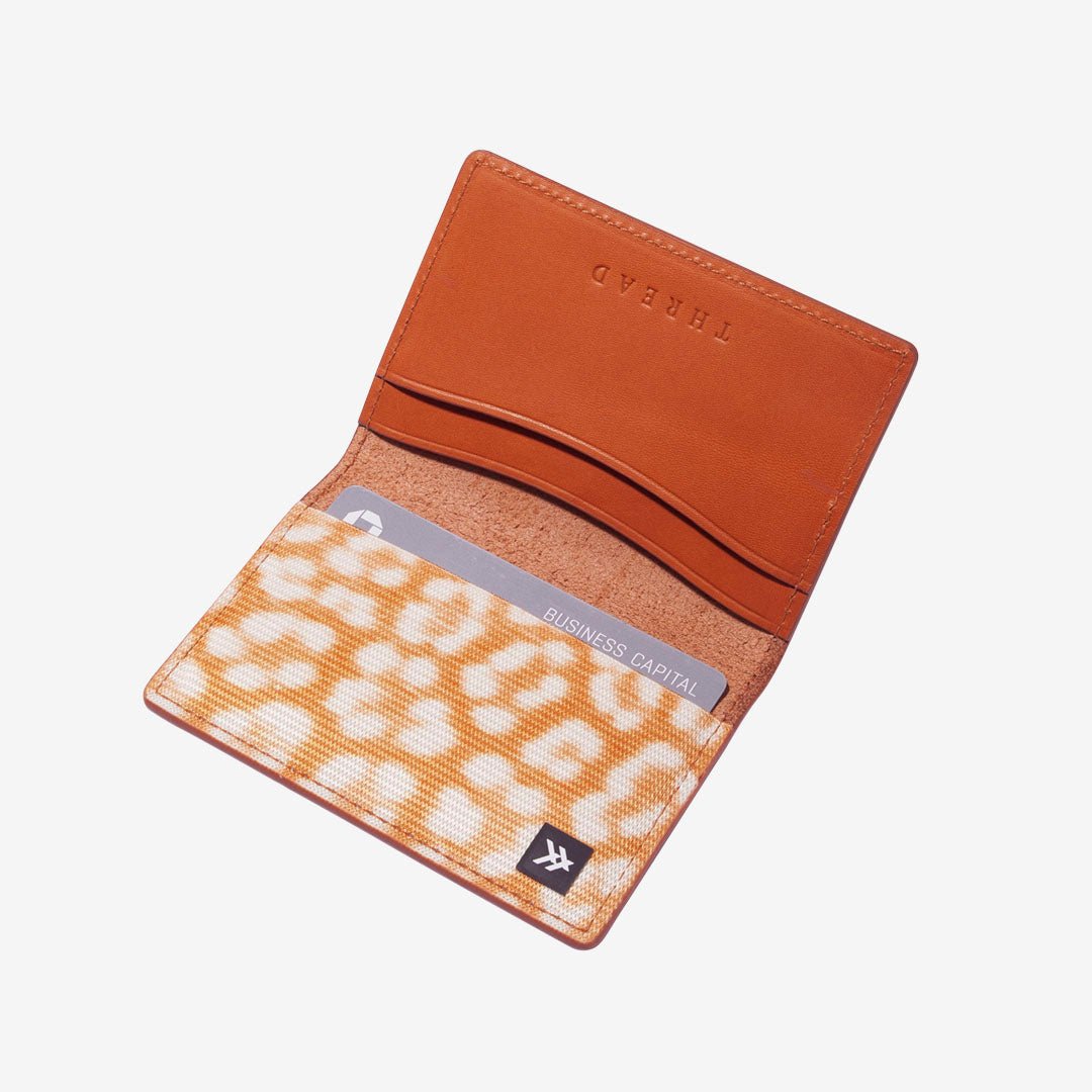 Brown leather bifold wallet with orange and white leopard print elastic